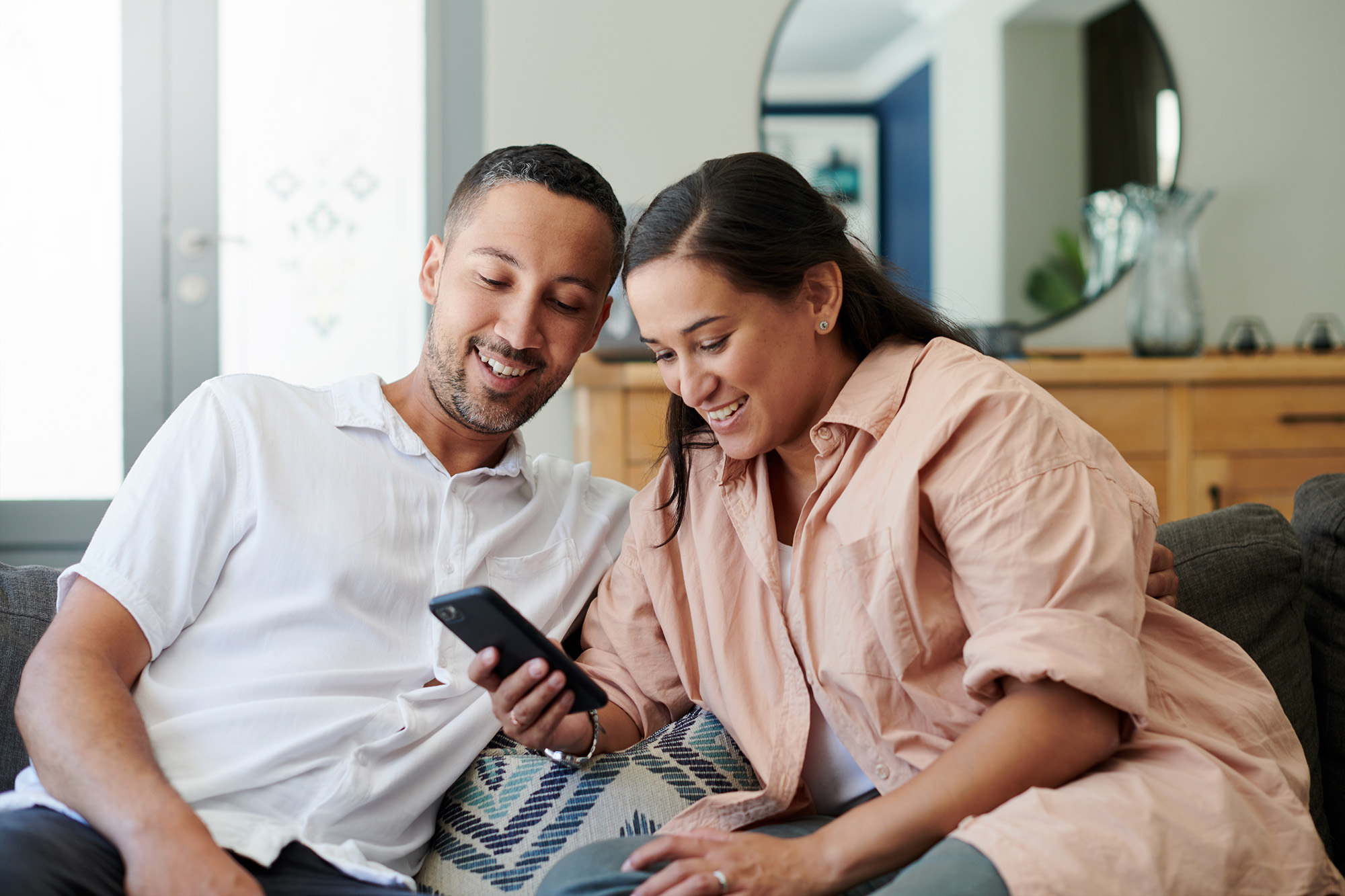 couple on couch checking cell phone