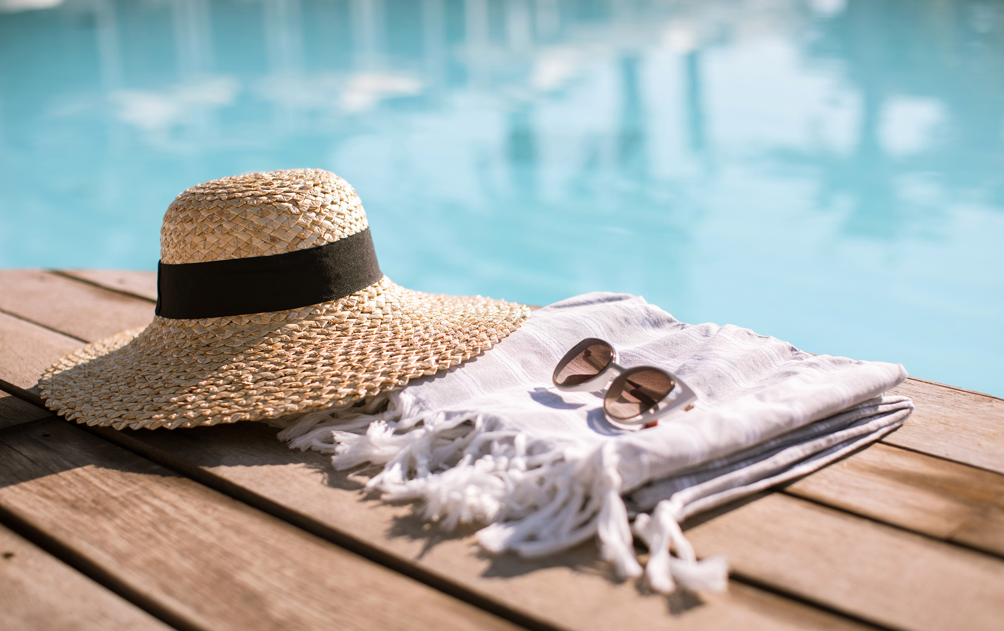 sun hat and sunglass by swimming pool