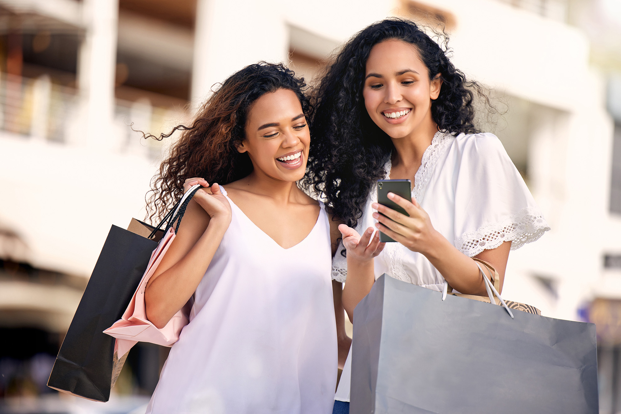 Women with shopping bags and checking cell phone