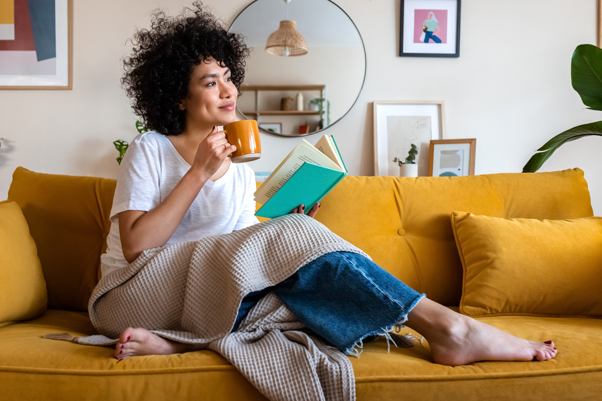 Woman on the couch with mug and book
